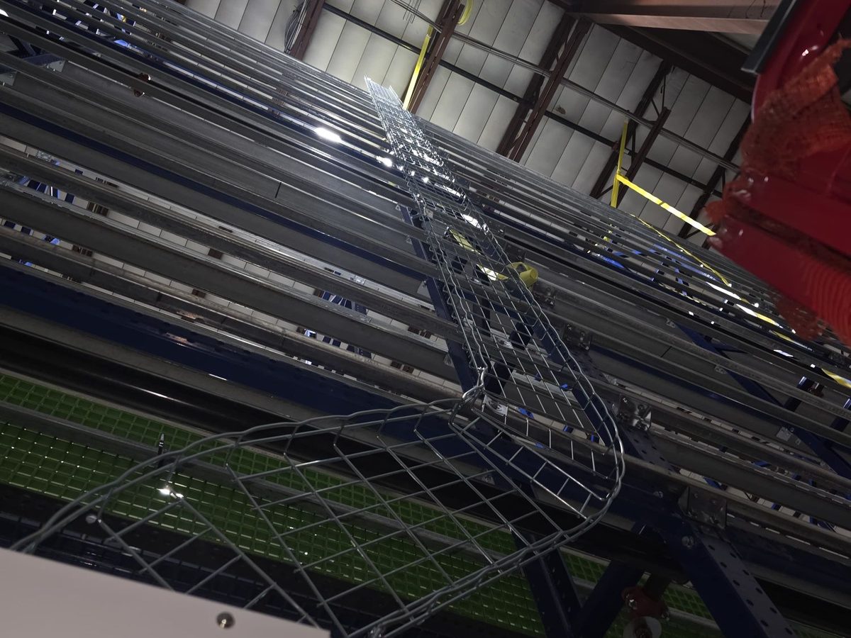 Basket cable tray routed up a multi-level warehouse racking structure